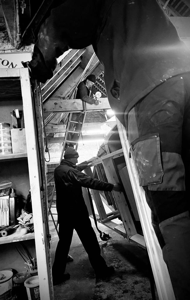 black and white image of man in barn flipping boat hull