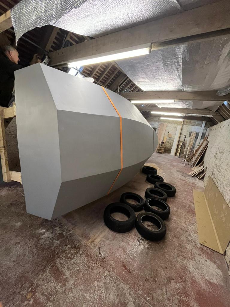 the grey underside hull of a boat with a cluster of tyres next to it