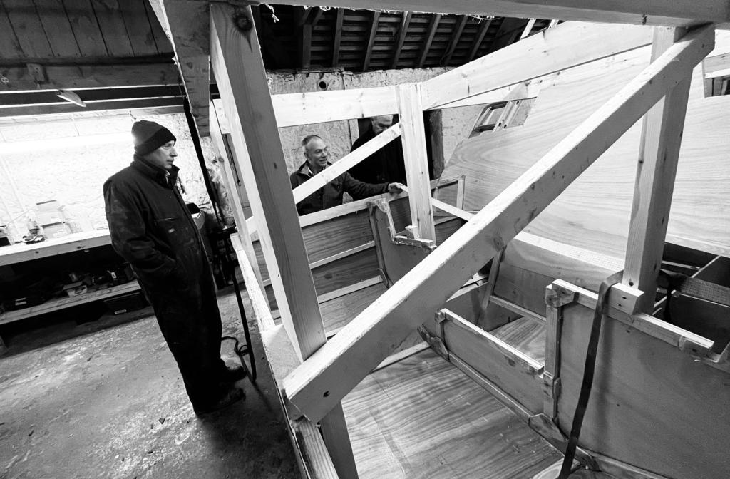black and white photo of two men building the frame of a boat